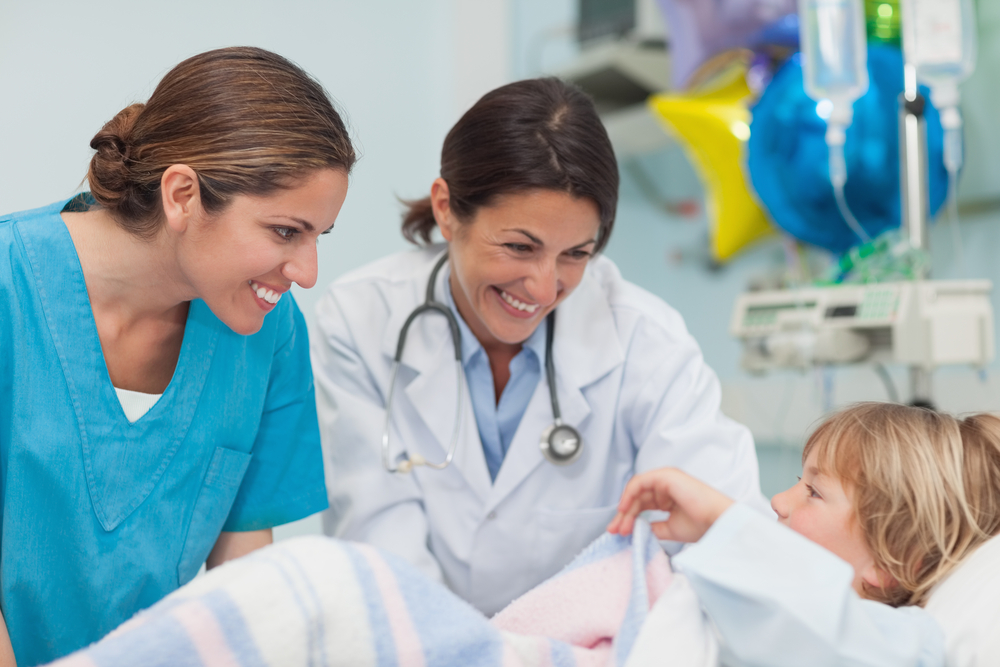 Doctor And Nurse Looking At A Child In Hospital Ward